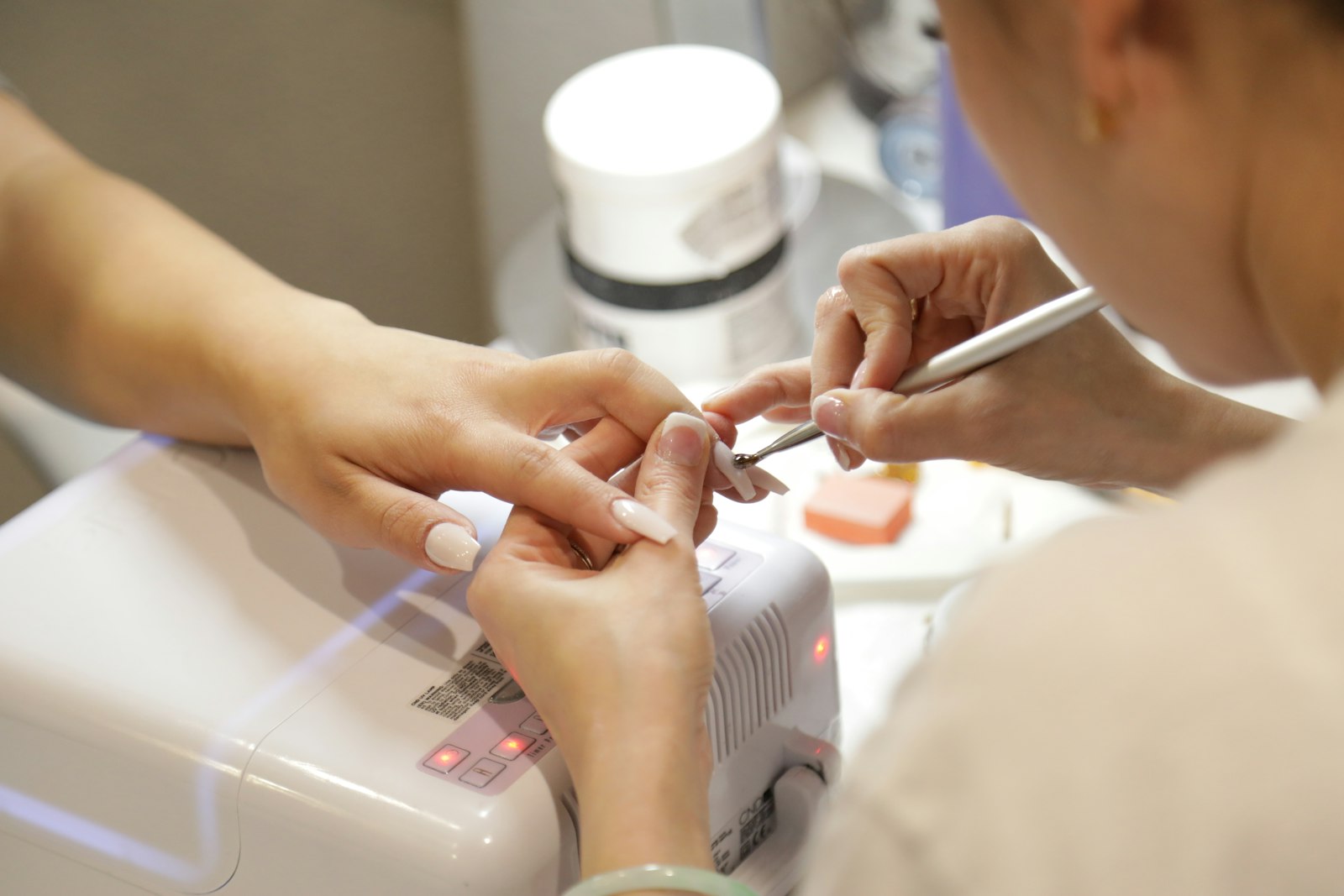 A nail technician working on a client's nails at a salon table
