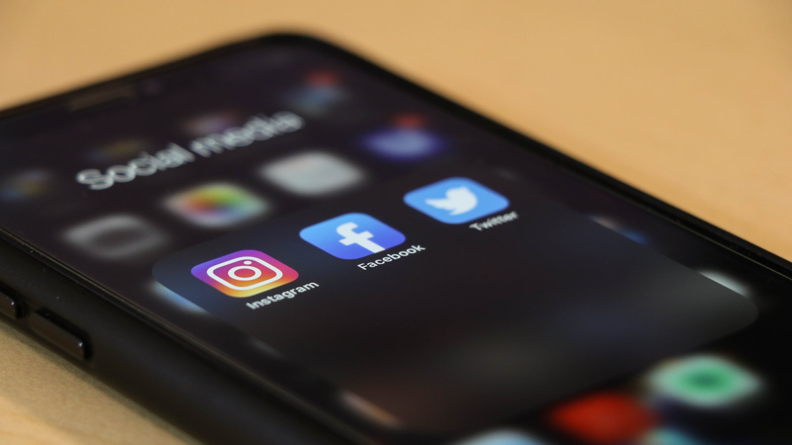 A phone screen showing social media apps on a wooden table