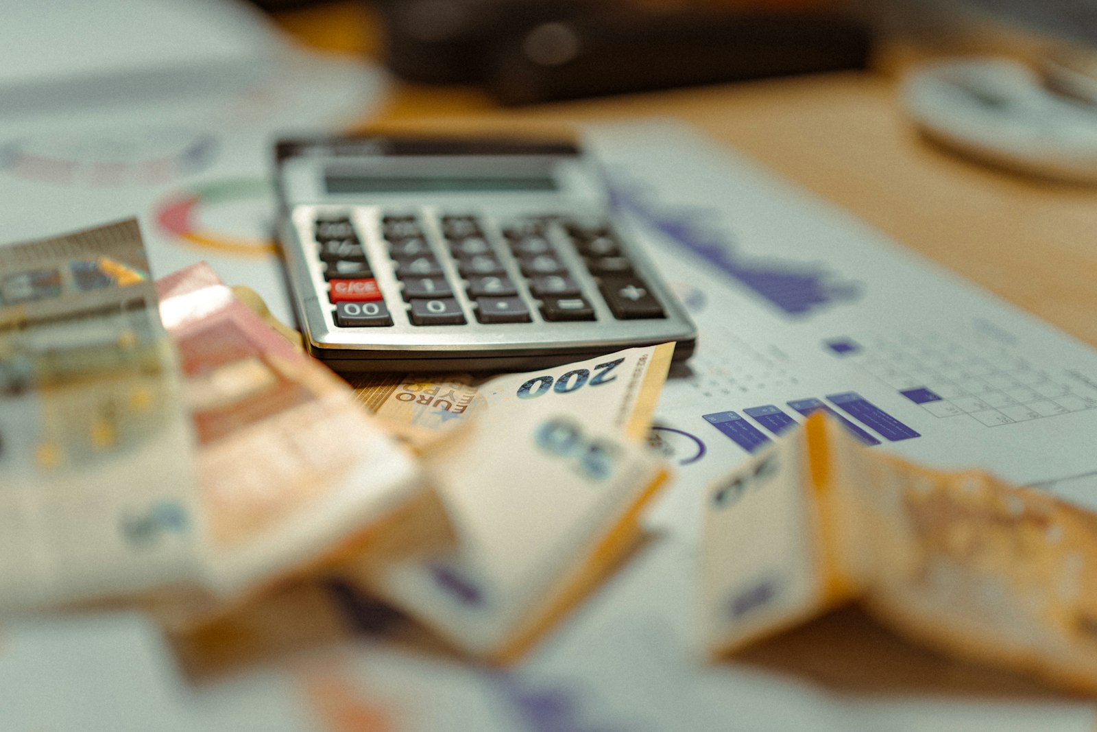 A calculator resting on banknotes and printed charts on a desk