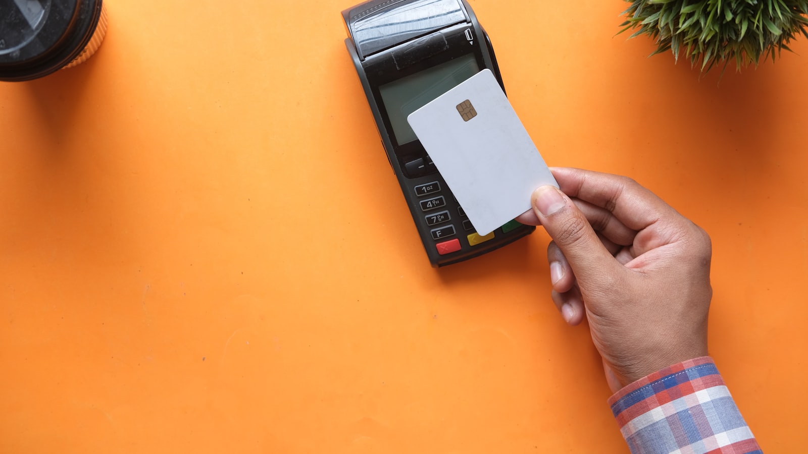 A hand holding a bank card over a payment terminal