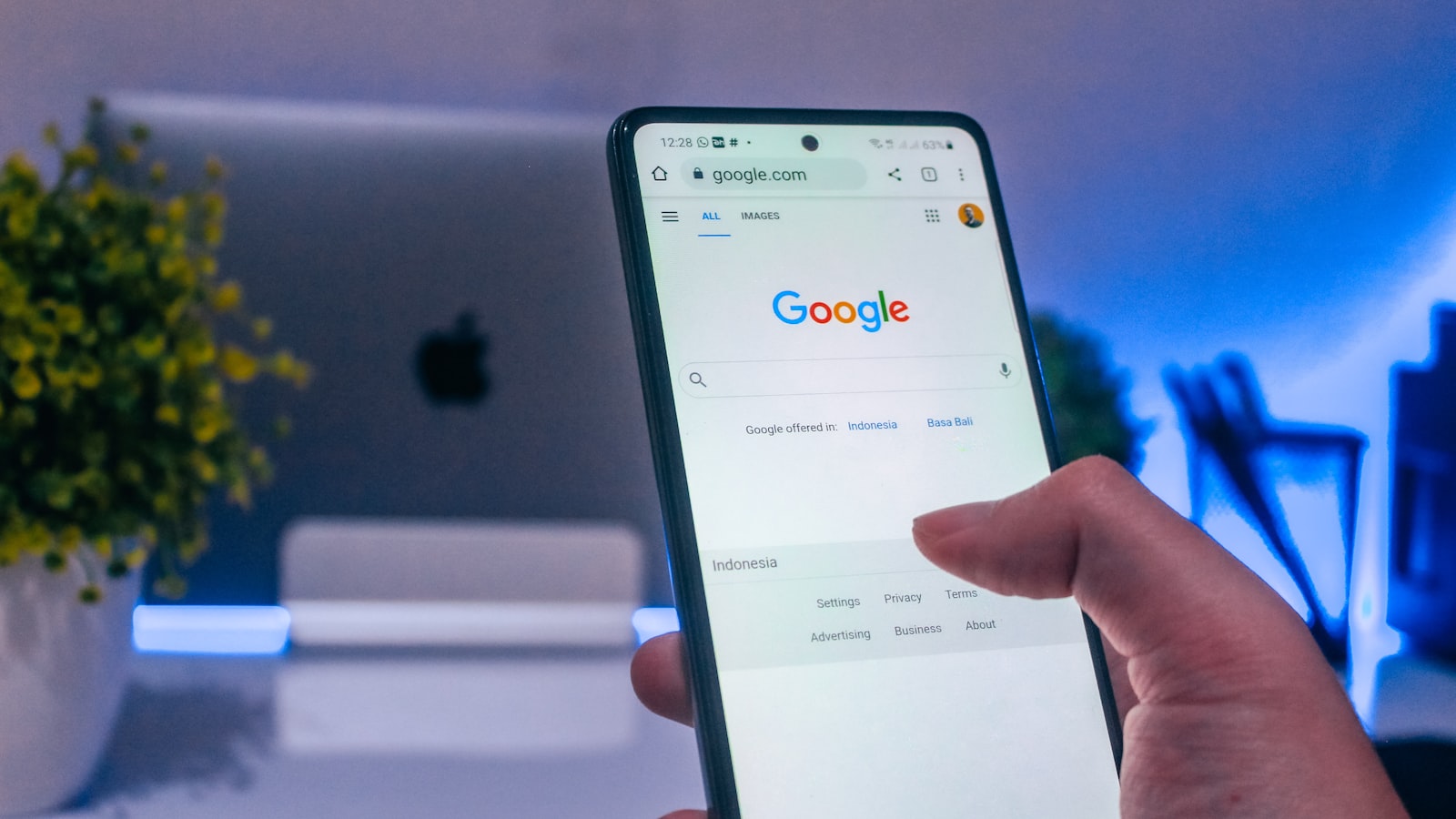 A hand holding a phone with Google search open