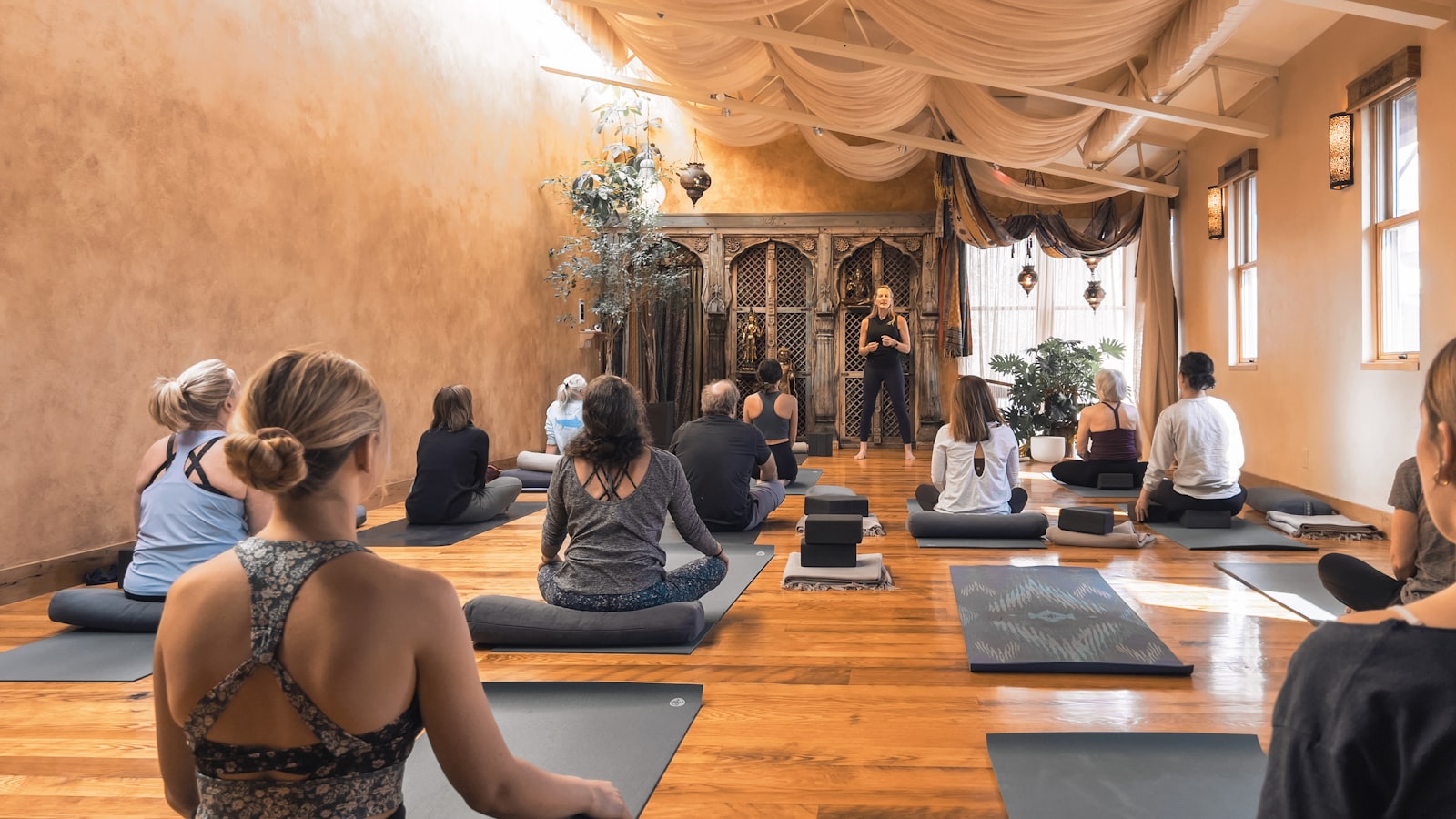 A yoga class seated on mats in a warm sunlit studio