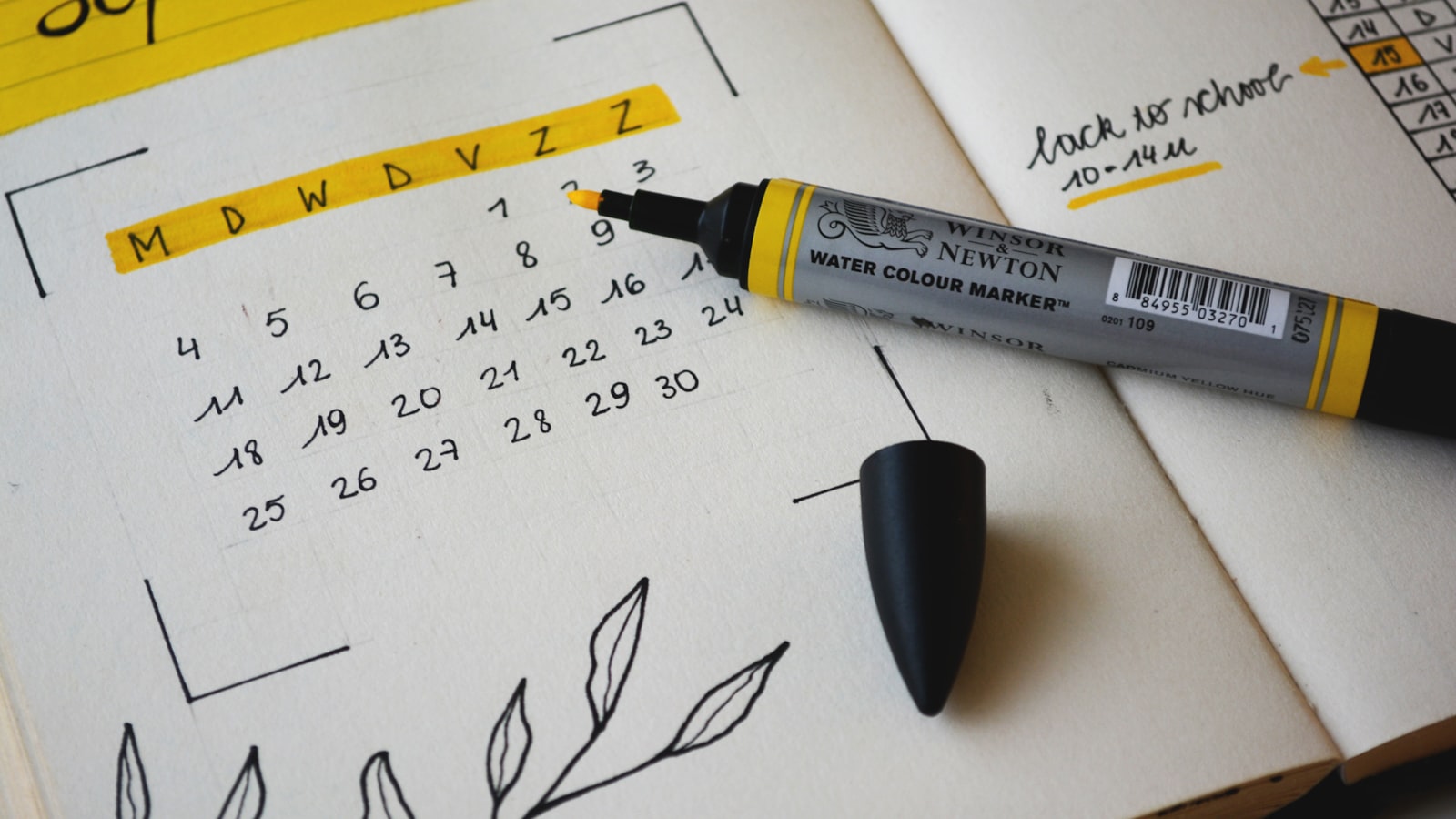A paper planner open on a desk with a pen